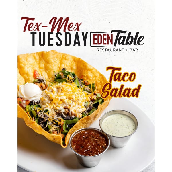 A taco salad in a crispy tortilla bowl with sour cream, salsa, and dressing on a white plate.